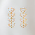 Pendientes largos Cuatro Latidos de filigrana momposina dorada con cuatro corazones tejidos.
