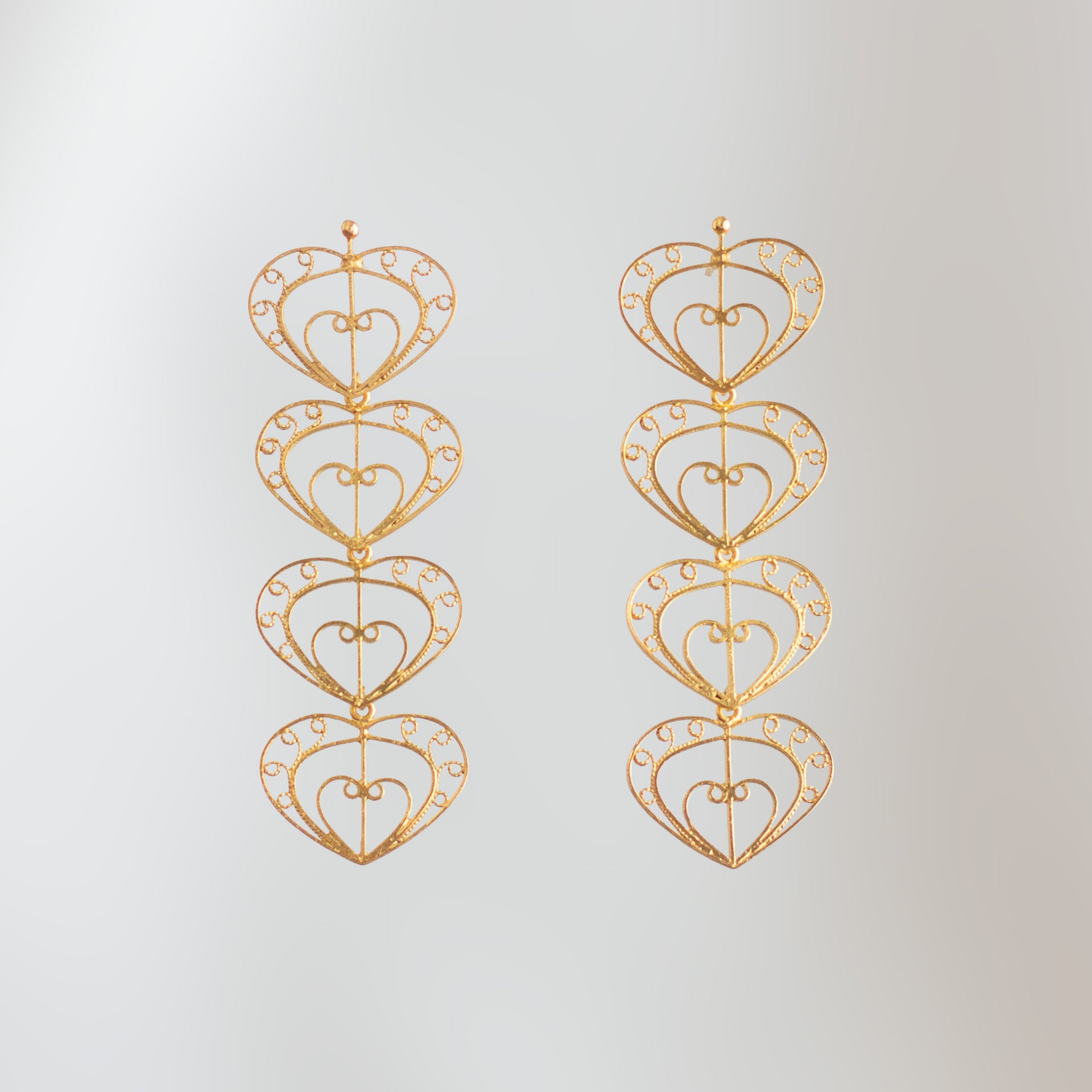 Pendientes largos Cuatro Latidos de filigrana momposina dorada con cuatro corazones tejidos.