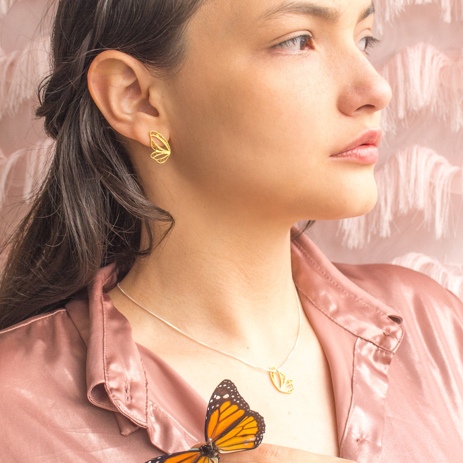 Modelo luciendo los pendientes topo media mariposa para un look femenino y minimalista.
